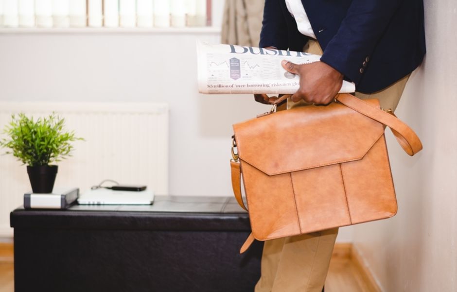 An image of a professional holding a briefcase and business trade press.