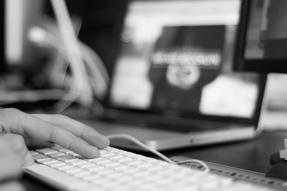 immagine in bianco e nero e mani che battono sulla tastiera di un pc