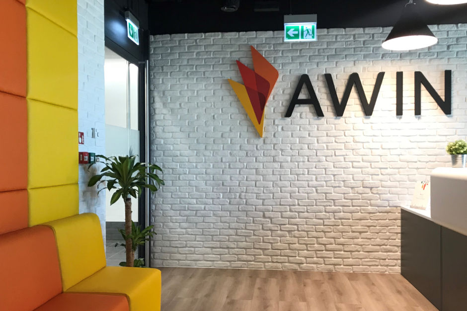 office wall made of white bricks with awin logo