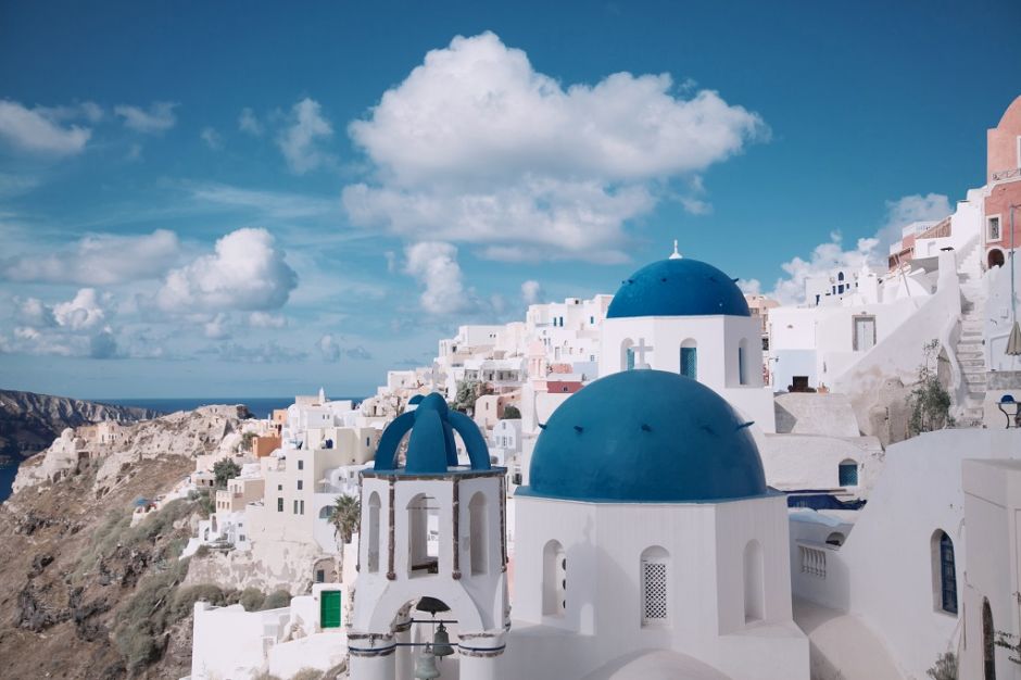 landscape with white houses and blue rooftops under a clear blue sky with puffy white clouds