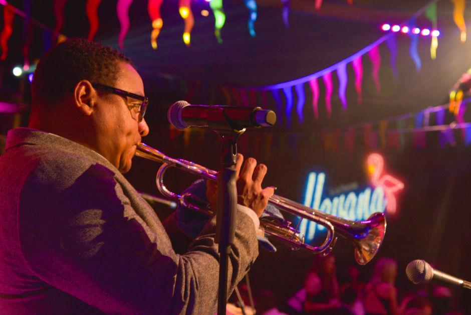 man playing an instrument in a club with colourful lights