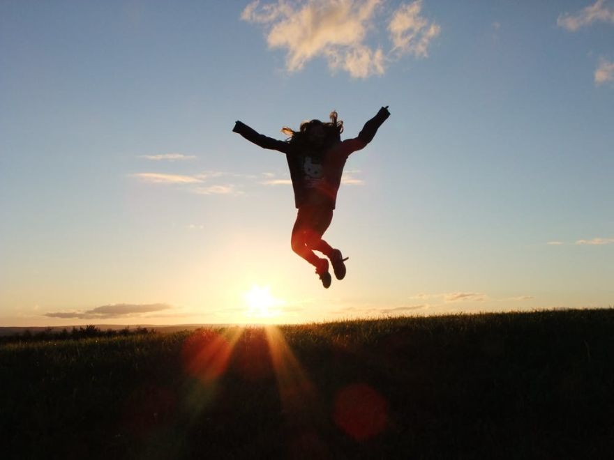 ragazza che salta al tramonto, in controluce