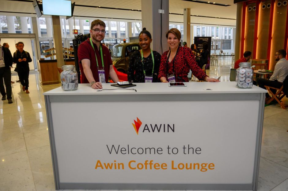 Drei Menschen hinter einem Counter mit Awin Logo