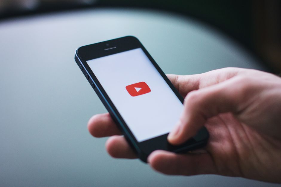 Hand hält iPhone mit YouTube Logo