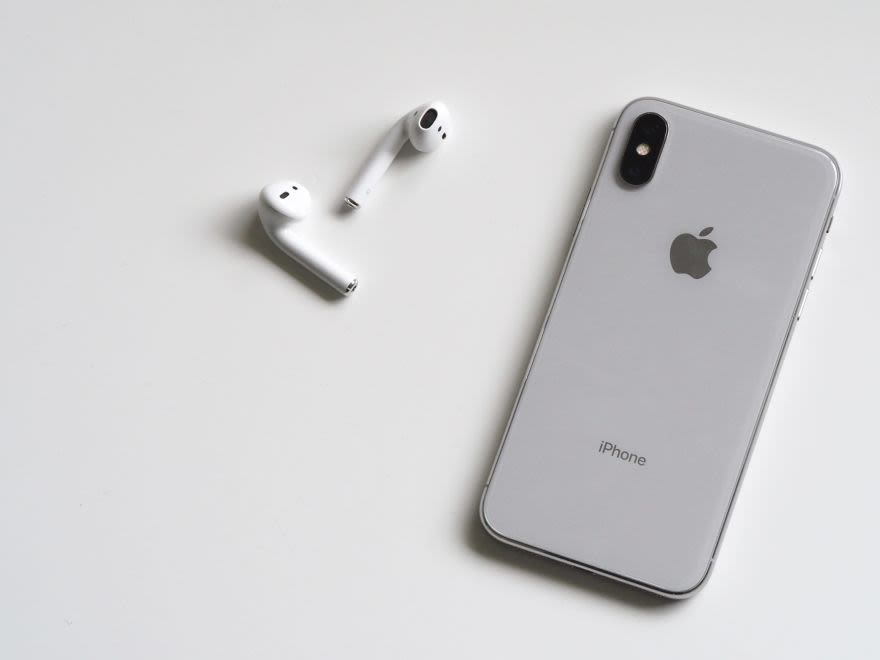 silbernes iPhone und Airpods auf weißer Unterlage