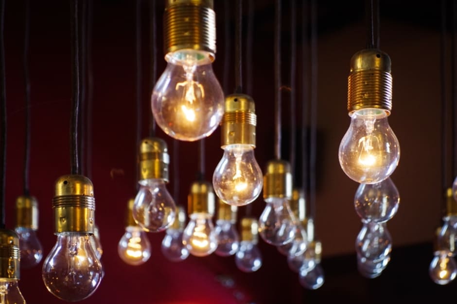An image of hanging lightbulbs at varying lengths, some lightbulbs are lit whilst others are not.