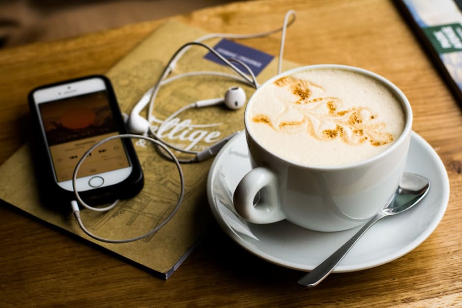 tazza di cappuccino con a fianco un iphone sintonizzato su un podcast