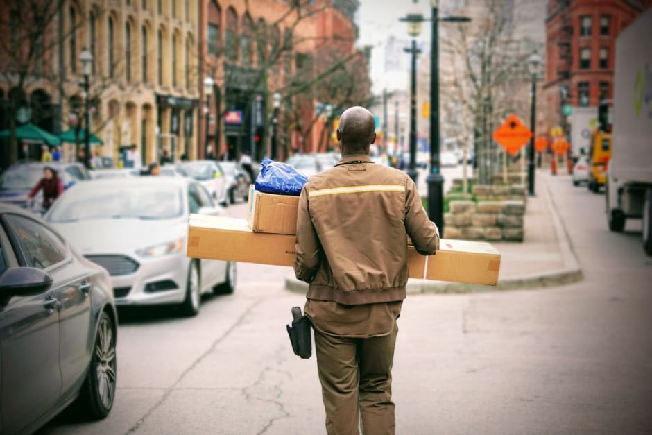 Man delivering boxes and parcels in city scape for online shopping retailer
