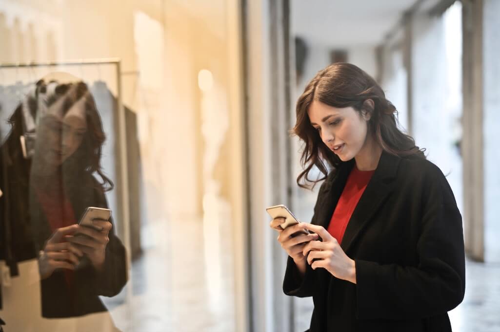Ragazza con il telefono in mano davanti alla vetrina di un negozio