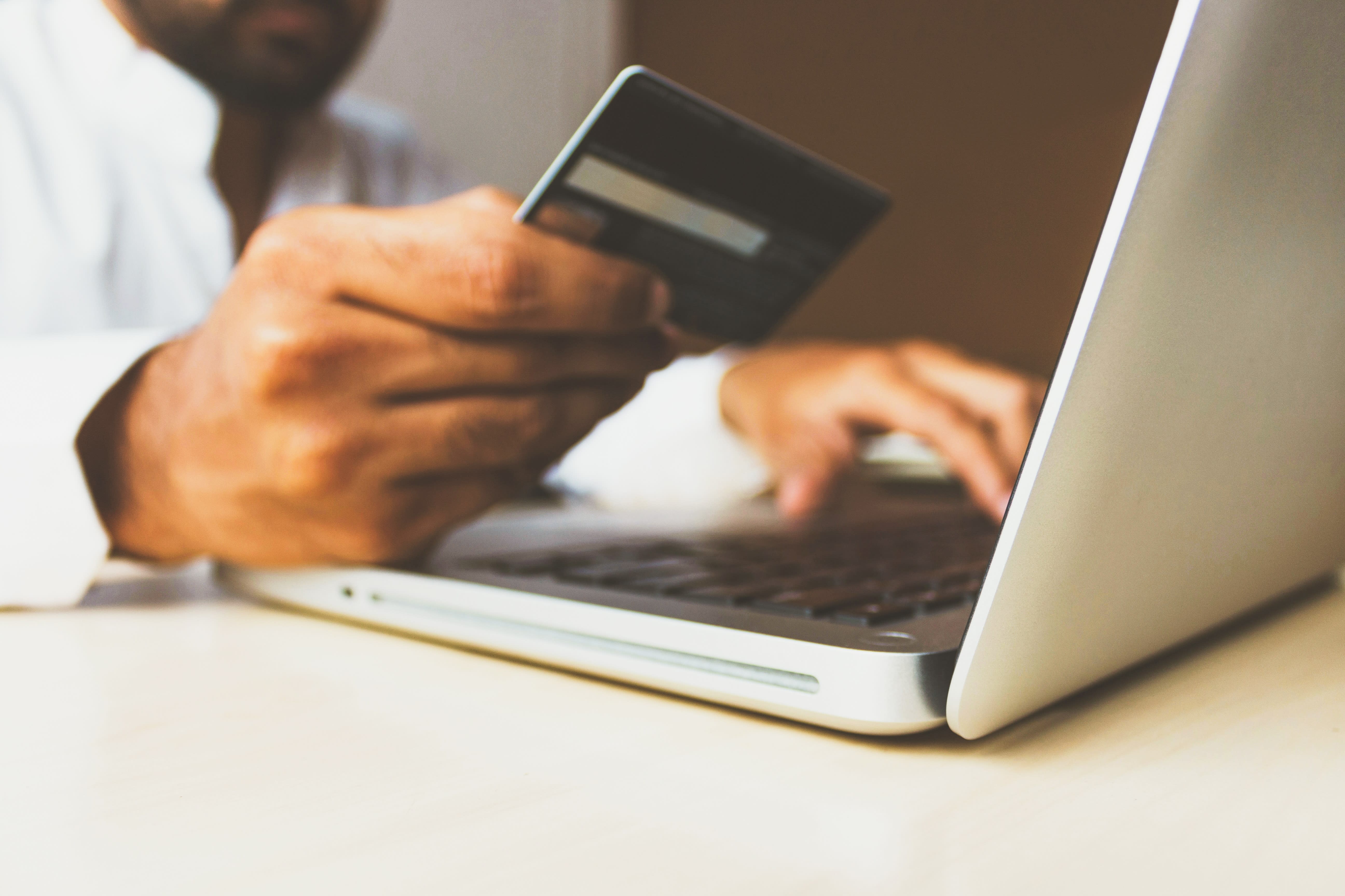 Mano che impugna una carta di credito mentre è al pc